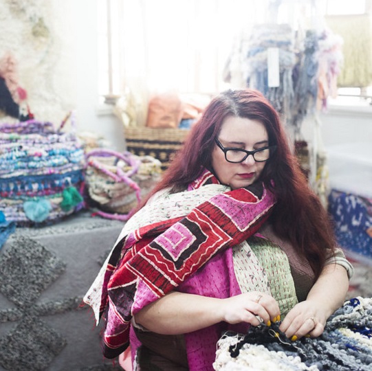 Artist Sky Carter sitting in studio working with hands - Fibre and textile artist. Surronded by colourful wool and woven baskets